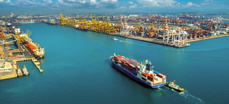 Aerial view of a large container port with cargo vessels, quay cranes and container yards